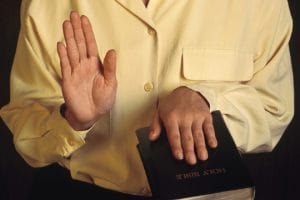 expert with hand on Bible