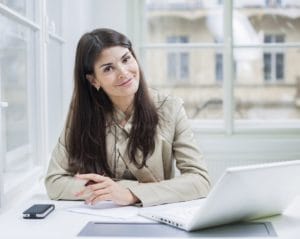 Portrait of confident businesswoman with laptop sitting at office desk