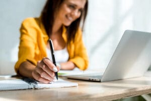 women with lap top and pen writing