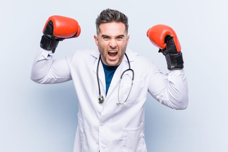 Caucasian doctor man wearing boxing gloves