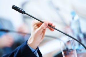 Microphone held in hand of person presenting to attorney audience